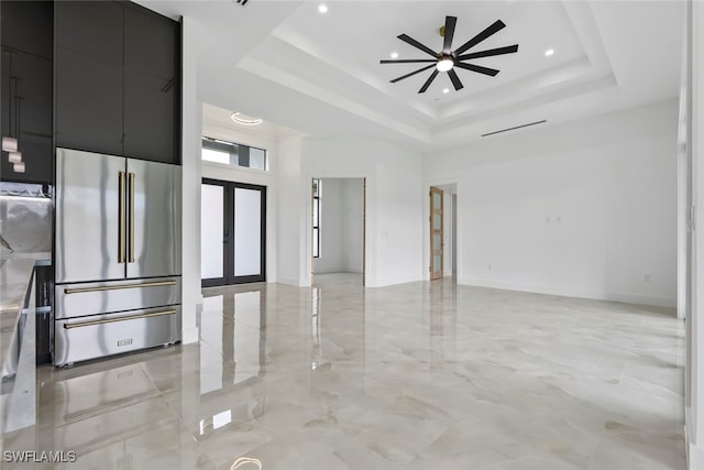 unfurnished room featuring a raised ceiling, a high ceiling, ceiling fan, and french doors