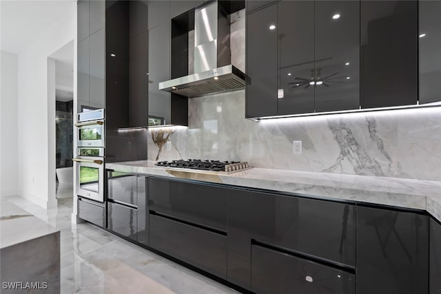 kitchen featuring gray cabinetry, wall chimney exhaust hood, stainless steel appliances, and tasteful backsplash