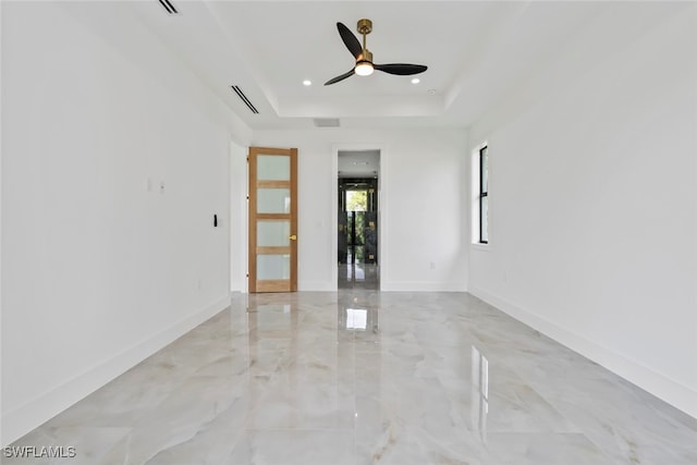 spare room featuring ceiling fan and a raised ceiling