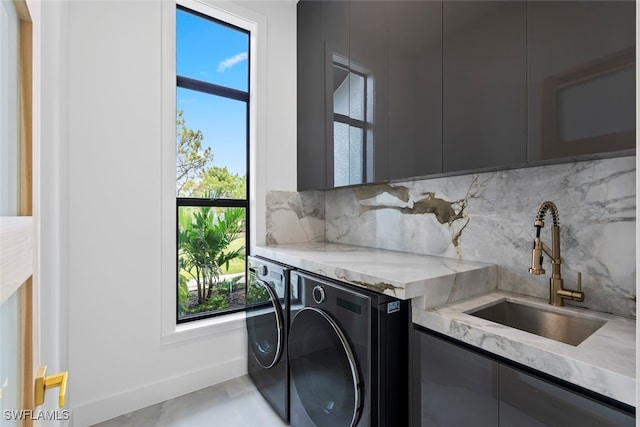 clothes washing area with cabinets, washer and dryer, and sink