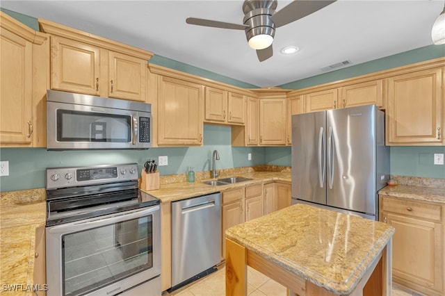 kitchen with ceiling fan, light stone counters, light tile patterned flooring, sink, and stainless steel appliances