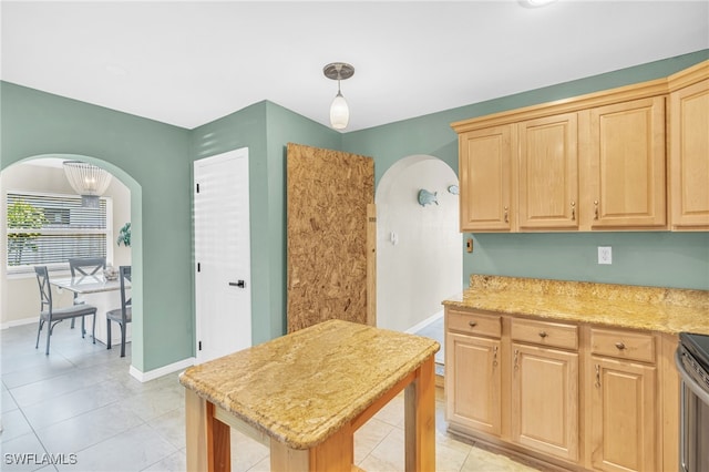 kitchen featuring light brown cabinetry, light stone countertops, decorative light fixtures, and light tile patterned floors