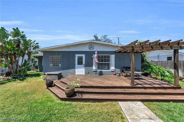 rear view of property featuring a wooden deck, a pergola, and a lawn