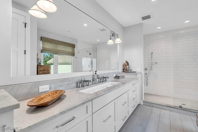 bathroom featuring tasteful backsplash, vanity, and a tile shower