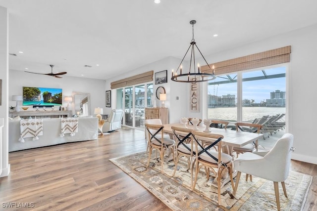 dining room with ceiling fan with notable chandelier and hardwood / wood-style flooring