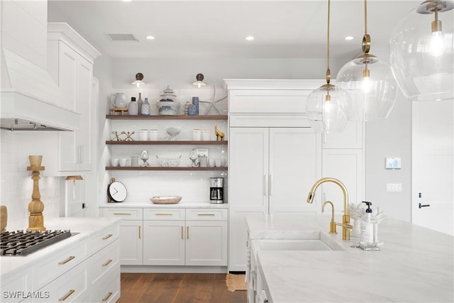 kitchen featuring pendant lighting, white cabinetry, backsplash, light stone counters, and stainless steel gas stovetop