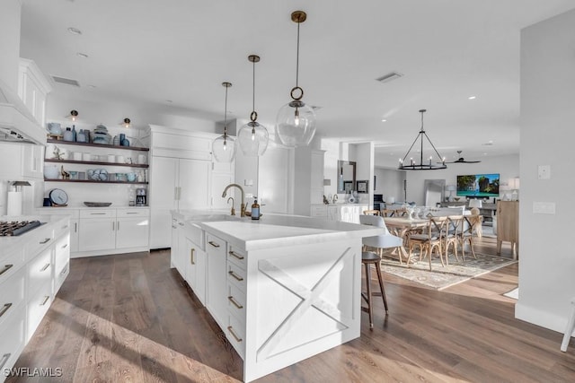 kitchen featuring dark wood-type flooring, white cabinetry, a kitchen bar, and a kitchen island with sink