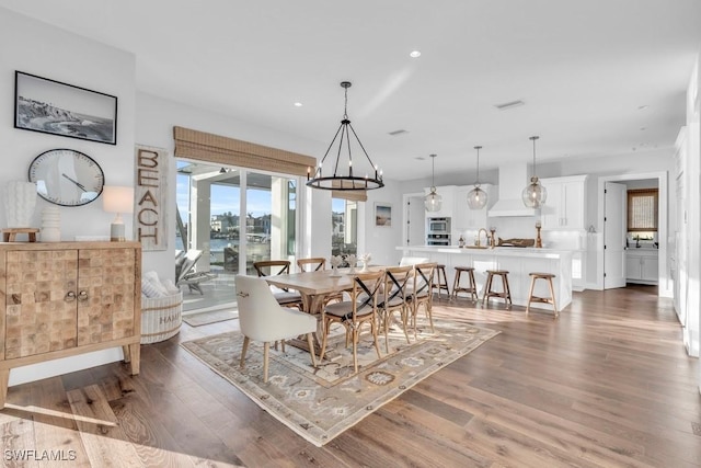 dining room featuring dark wood-type flooring, sink, and an inviting chandelier