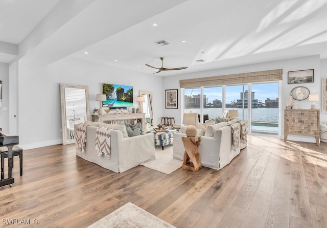 living room featuring ceiling fan, a fireplace, and light hardwood / wood-style flooring