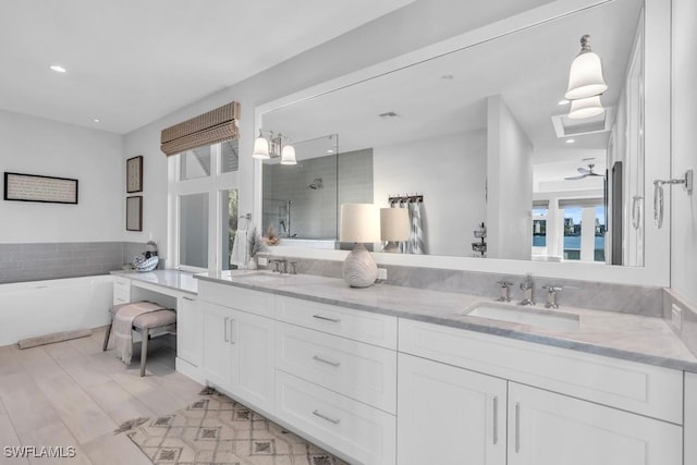 bathroom with ceiling fan, a healthy amount of sunlight, separate shower and tub, and vanity