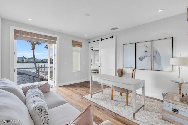 home office with a water view, a barn door, and light hardwood / wood-style floors