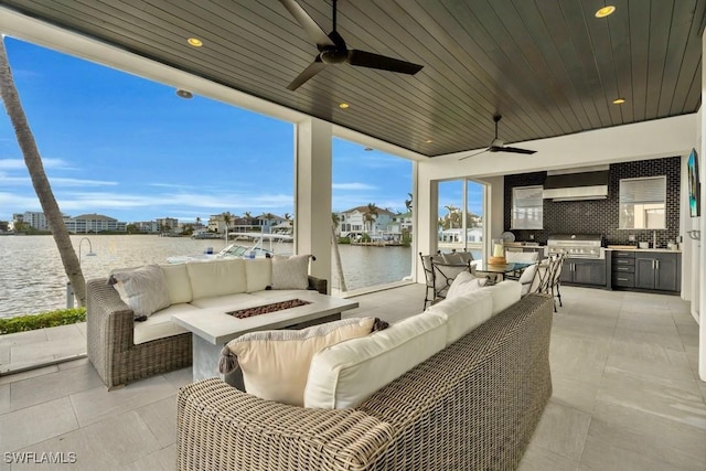 view of patio featuring a water view, an outdoor kitchen, and an outdoor living space with a fire pit