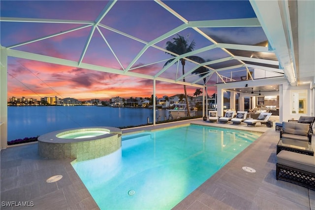 pool at dusk with a water view, a patio, glass enclosure, and an in ground hot tub