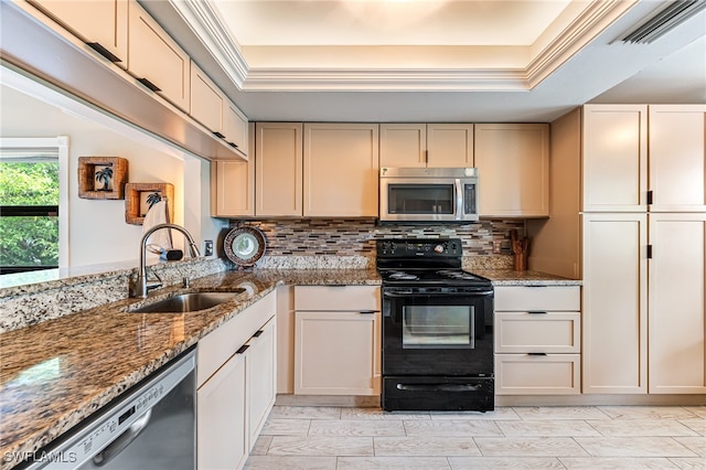 kitchen with a tray ceiling, sink, stainless steel appliances, and light stone counters