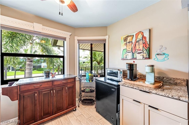 kitchen featuring ceiling fan, light wood-type flooring, refrigerator, and light stone countertops