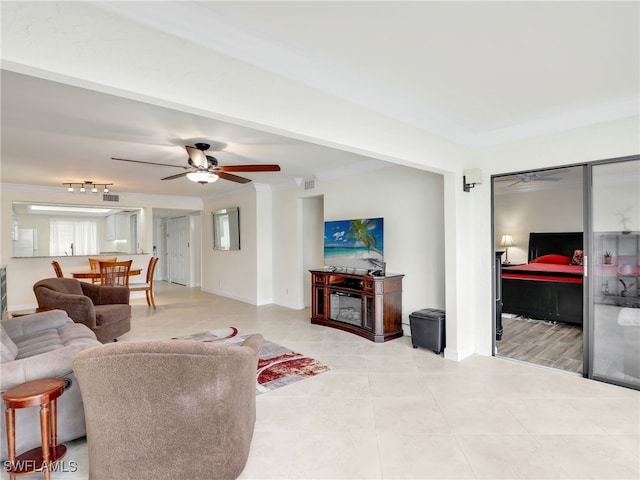 living area featuring crown molding, light tile patterned flooring, a ceiling fan, and visible vents