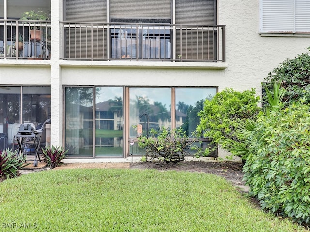 exterior space featuring a yard, stucco siding, and a balcony