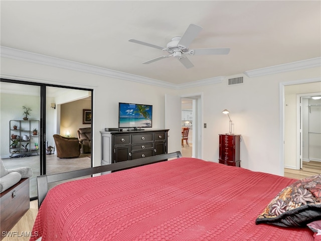 bedroom with visible vents, crown molding, ceiling fan, light wood-style floors, and a closet