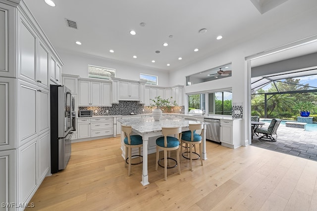 kitchen with appliances with stainless steel finishes, a kitchen bar, light wood-type flooring, and a center island