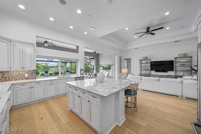 kitchen featuring light hardwood / wood-style flooring, a kitchen breakfast bar, ceiling fan, and a center island