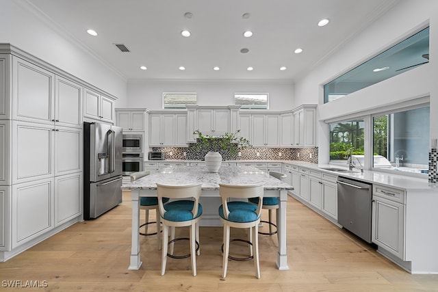 kitchen featuring ornamental molding, stainless steel appliances, a wealth of natural light, and a kitchen island