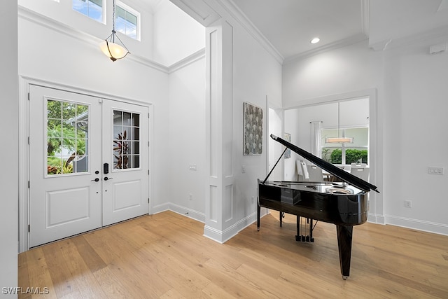 foyer entrance with a high ceiling, ornamental molding, light hardwood / wood-style flooring, and french doors