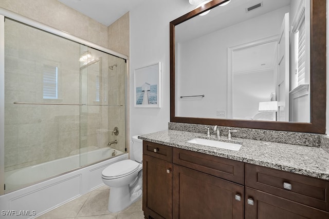 full bathroom with bath / shower combo with glass door, vanity, toilet, and tile patterned floors