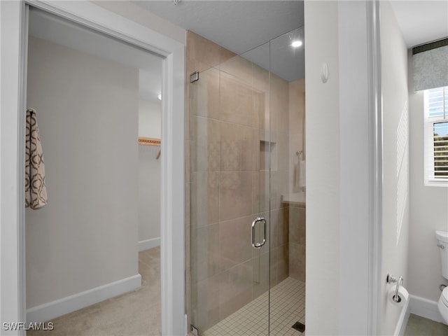 bathroom with a shower with door and toilet