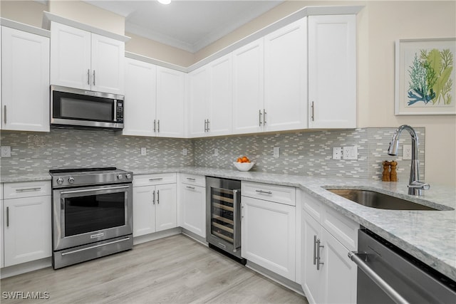 kitchen featuring beverage cooler, white cabinets, and appliances with stainless steel finishes