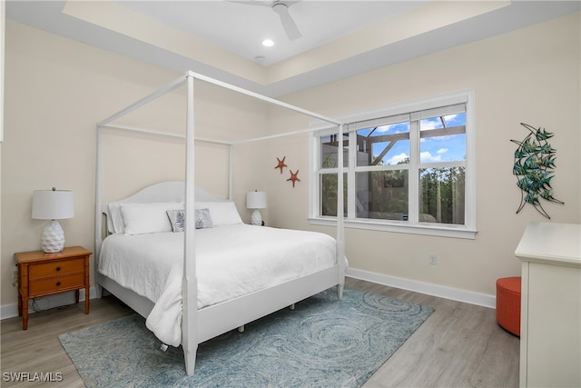 bedroom featuring ceiling fan, a raised ceiling, and hardwood / wood-style floors