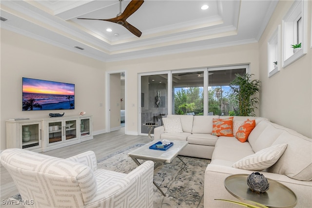 living room with light hardwood / wood-style floors, ornamental molding, and ceiling fan