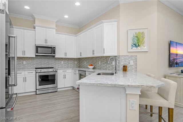 kitchen featuring white cabinets, kitchen peninsula, appliances with stainless steel finishes, and sink