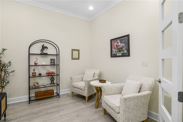 living area with light wood-type flooring and ornamental molding