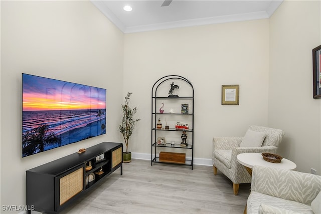 living area with crown molding and light hardwood / wood-style flooring