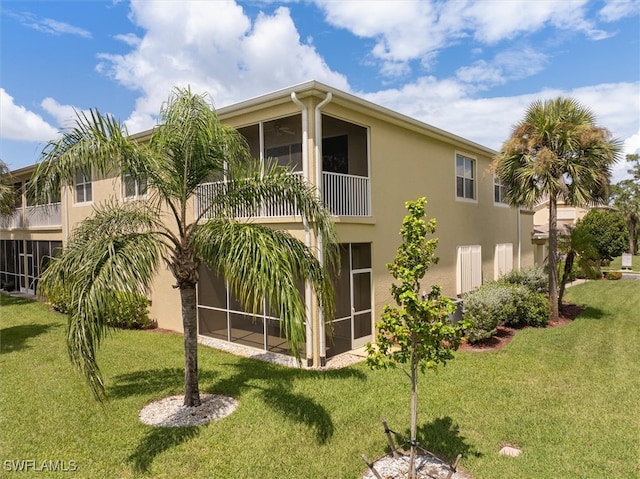 rear view of house with a balcony and a lawn