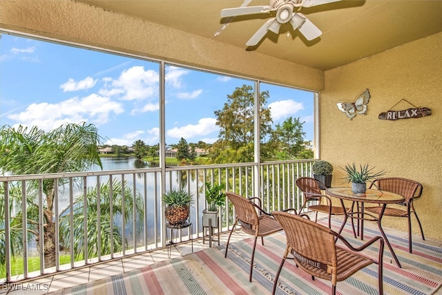 sunroom / solarium with a water view and ceiling fan