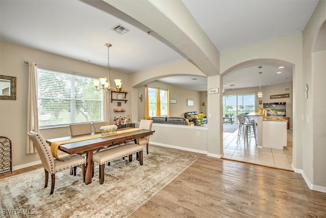 dining space with light wood-type flooring and an inviting chandelier