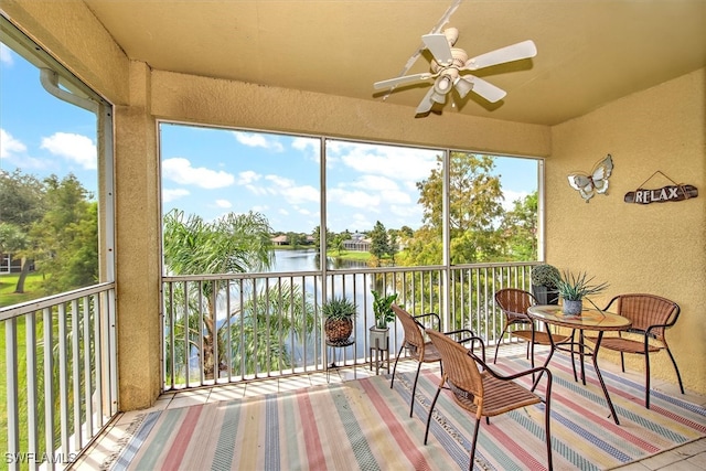 sunroom featuring a water view and ceiling fan