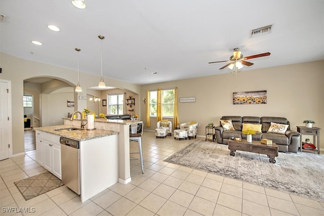 kitchen with ceiling fan, white cabinets, sink, stainless steel dishwasher, and decorative light fixtures