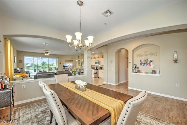 dining room featuring ceiling fan with notable chandelier and hardwood / wood-style flooring