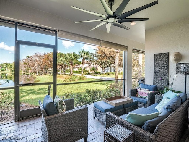 sunroom / solarium featuring ceiling fan and a water view