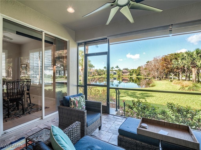 sunroom / solarium featuring a water view, plenty of natural light, and ceiling fan