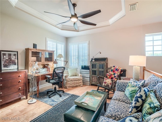 home office featuring a raised ceiling, ceiling fan, crown molding, and light wood-type flooring