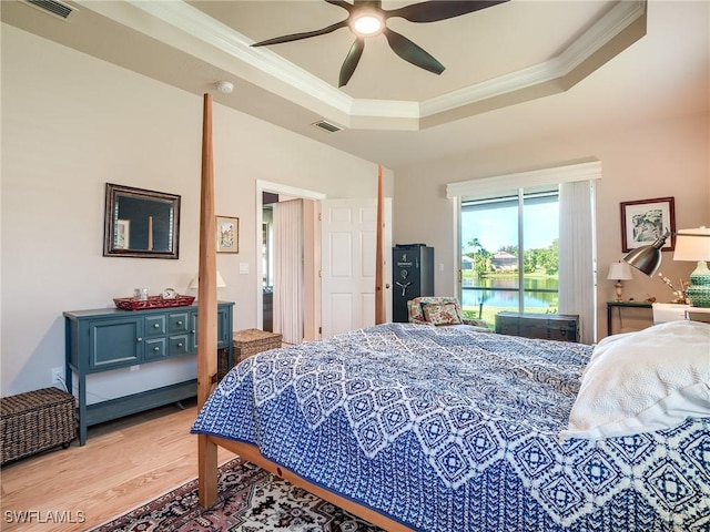 bedroom with crown molding, ceiling fan, a raised ceiling, and light wood-type flooring