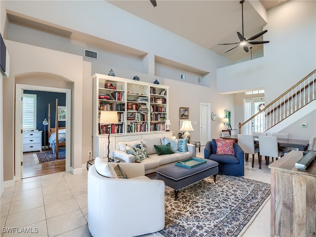 tiled living room with ceiling fan and a towering ceiling