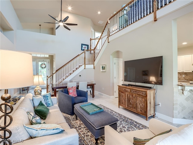 living room featuring light tile patterned flooring, ceiling fan, and a high ceiling