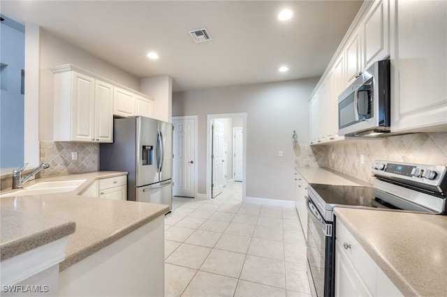 kitchen with sink, light tile patterned floors, appliances with stainless steel finishes, decorative backsplash, and white cabinets