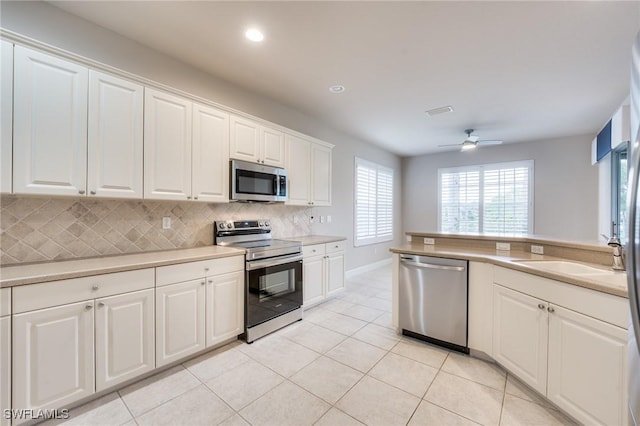 kitchen featuring white cabinetry, sink, decorative backsplash, ceiling fan, and stainless steel appliances