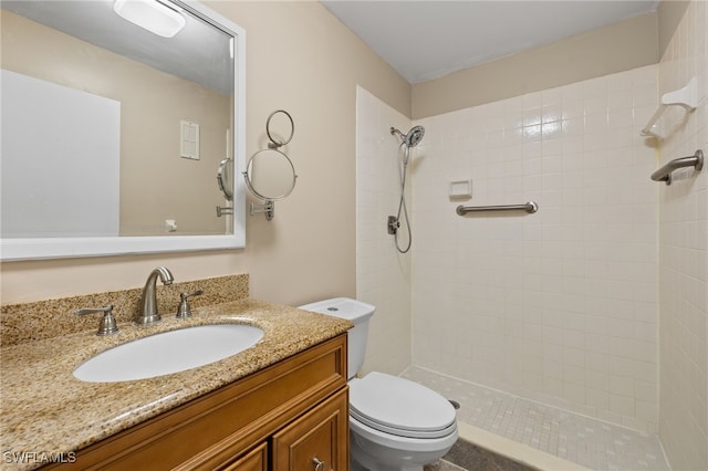 bathroom with tiled shower, vanity, and toilet