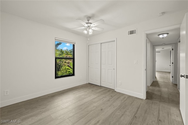 unfurnished bedroom with a closet, light hardwood / wood-style floors, and ceiling fan